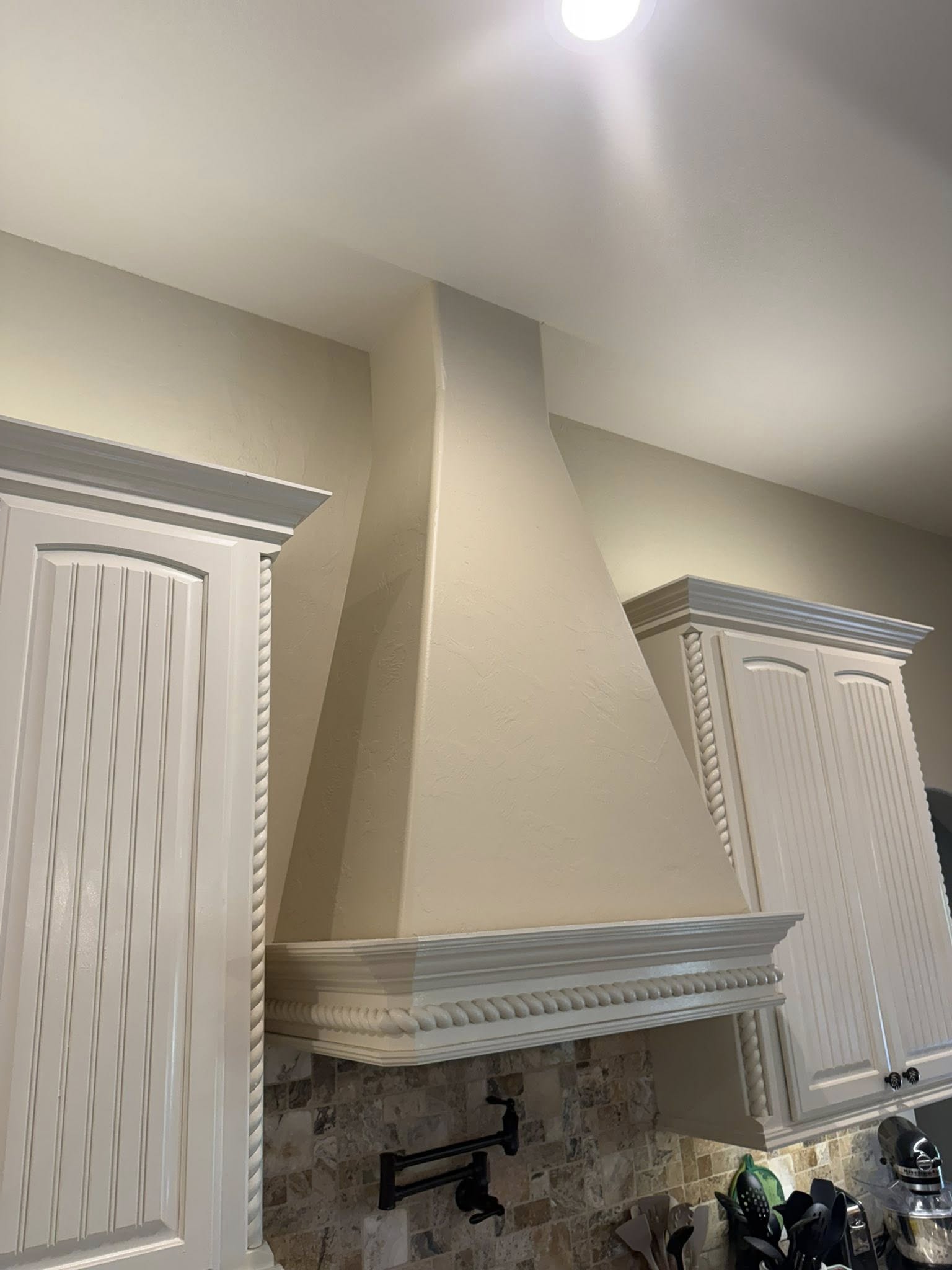 Cream-colored kitchen cabinets and range hood before refinishing