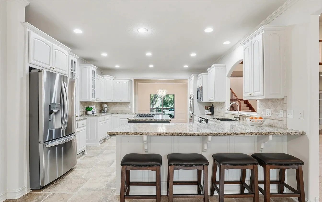 Bright white kitchen with painted cabinets and a granite breakfast bar