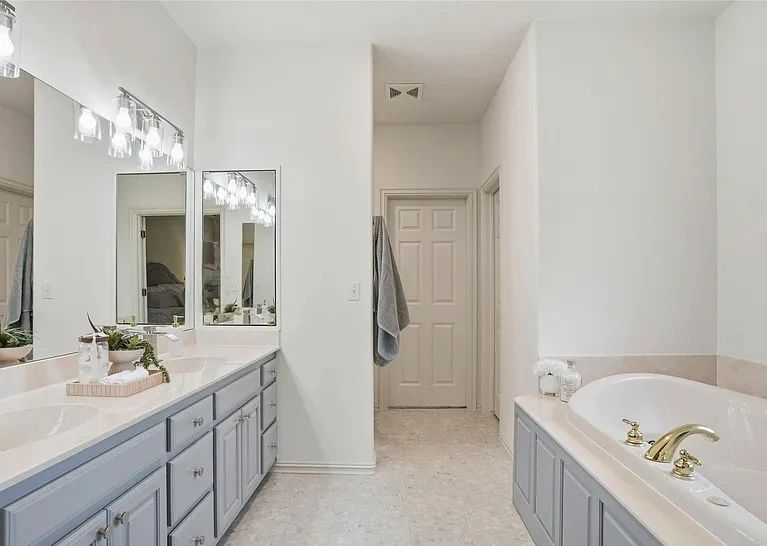 Master bathroom with a painted gray vanity and soaking tub